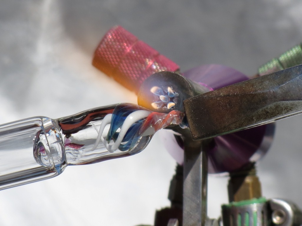 An artist blowing a piece of glass to make a beautiful pendant